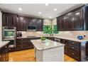 Gourmet kitchen featuring dark cabinetry, a center island, stainless steel appliances, and hardwood floors at 6795 Preston Glen Dr, Alpharetta, GA 30005