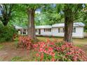 Beautiful home exterior with green roof, mature trees and landscaping with colorful flowers at 5766 Macland Rd, Powder Springs, GA 30127