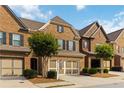 Attractive brick townhome boasts a two-car garage, complemented by lush green landscaping at 4150 Cedar Bridge Walk, Suwanee, GA 30024