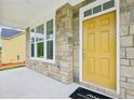 Close-up of the front door and stone facade with a yellow front door and an Ashton Woods welcome mat at 5377 Heron Bay Blvd, Locust Grove, GA 30248