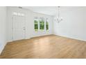 Bright living room with hardwood floors, white walls, modern chandelier, and large windows overlooking backyard at 5377 Heron Bay Blvd, Locust Grove, GA 30248