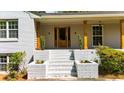 Inviting covered front porch with brick columns, steps, and manicured landscaping for curb appeal at 7300 Wynhill Dr, Sandy Springs, GA 30328