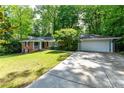 Well-maintained brick ranch home with a lush lawn, a paved driveway, and an attached two-car garage at 6651 Castleton Dr, Atlanta, GA 30328