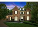 Twilight view of an elegant two-story brick home with manicured lawn and lush landscaping at 4750 Spring Wood Trce, Cumming, GA 30041