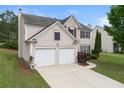 Angle view of tan two-story home with attached two-car garage, brick and siding, and a well-manicured lawn at 550 Bayswater Way, Suwanee, GA 30024