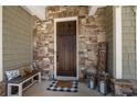 Inviting front porch with stone accents, a wood door, and a cozy bench creating a warm entry at 3883 Wakefield Hall Se Sq, Smyrna, GA 30080