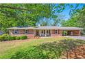 All brick ranch home featuring a covered parking area and meticulously maintained lawn at 205 Corinth Ct, Roswell, GA 30075