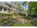 Expansive backyard with stone stairs, lush landscaping, and an umbrella-covered patio area at 4979 Shadow Glen Ct, Dunwoody, GA 30338