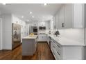 Modern kitchen with stainless steel appliances, white cabinetry, a kitchen island, and hardwood floors at 4979 Shadow Glen Ct, Dunwoody, GA 30338