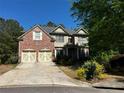 Charming two-story home featuring a brick facade, two-car garage, and manicured landscaping at 5679 Coopers Glen Ct, Mableton, GA 30126