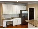 Bright kitchen featuring white cabinets, stainless steel appliances, granite countertops, and a built-in desk at 5679 Coopers Glen Ct, Mableton, GA 30126