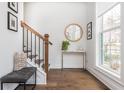 Inviting entryway with wood floors, stairs, wood and iron railings, bench, decor and natural light at 472 Burton Dr, Alpharetta, GA 30009