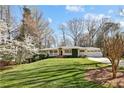 Ranch home with a lush front yard and mature trees on a sunny day showcasing curb appeal at 1299 W Wesley Nw Rd, Atlanta, GA 30327