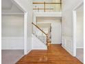 Bright foyer featuring hardwood floors, a staircase, and views of the second-floor landing at 1520 Ethans Way, Mcdonough, GA 30252
