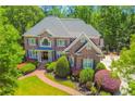 Beautiful brick home featuring mature landscaping, a manicured lawn, and a brick walkway to the front door at 2644 Nutwood Trce, Duluth, GA 30097