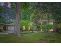Brick home exterior, illuminated by landscape lighting with mature trees and lush green lawn at 2687 Goodfellows Rd, Tucker, GA 30084