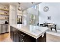 Kitchen with black island with marble countertops, stainless appliances and pendant lighting at 11189 Serenbe Ln, Chattahoochee Hills, GA 30268