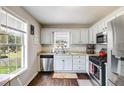 Bright kitchen featuring a window over the sink, white cabinets, stainless steel appliances, and hardwood floors at 115 N Loblolly Xing, Temple, GA 30179