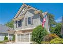Side view of a gray two-story home with an American flag, showcasing its manicured landscaping at 235 Cornerstone Dr, Woodstock, GA 30188