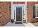 Close-up of a classic black front door with sidelights, elegant lighting fixtures, and potted plants at 4044 Kenway Se Pl, Smyrna, GA 30082