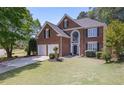 Charming two-story brick home with a well-manicured lawn, mature trees, and a classic front door at 4044 Kenway Se Pl, Smyrna, GA 30082