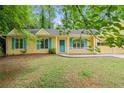 Yellow house with blue shutters and front porch sitting on a grassy lot at 502 Knollwood Pl, Woodstock, GA 30188
