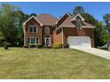 Lovely brick home showcasing an attached two-car garage and lush green front yard at 2246 Carrington Dr, Ellenwood, GA 30294