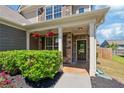 Charming covered front porch with stone columns and lush plantings at 3625 New River Ct, Cumming, GA 30040
