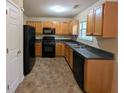 Efficient kitchen featuring wood cabinets, black appliances, and tile flooring at 3413 Creekview Dr, Rex, GA 30273