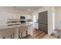 Well-lit kitchen boasts granite countertops, stainless steel appliances, an island with stools, and wood flooring at 175 Silverton Dr, Dacula, GA 30019