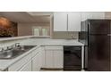 Kitchen featuring white countertops and cabinets with black appliances, open to the living area at 964 Chapman Ln, Stone Mountain, GA 30088