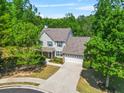 Aerial view of a well-maintained two-story home nestled among lush trees, with a spacious driveway at 182 Garden Manor Ct, Loganville, GA 30052