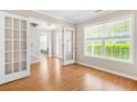 An open living room features hardwood flooring, white trim, and French doors leading to the foyer at 182 Garden Manor Ct, Loganville, GA 30052