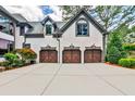 Three-car garage features decorative doors and exterior coach lights at 1114 Waterford Green Pt, Marietta, GA 30068