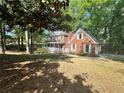 Two story red brick home with white trim and shutters surrounded by mature trees at 894 Oak Rd, Lawrenceville, GA 30044