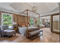 Spacious main bedroom with wood paneling, hardwood floors, tray ceilings and a seating area at 4030 Scenic View Ct, Cumming, GA 30028