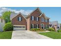 Two-story brick home boasting an attached garage, manicured lawn, and charming architectural details at 1632 Chadwick Ridge Dr, Lawrenceville, GA 30043