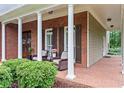 Covered front porch with brick flooring, columns, and comfortable seating area at 4592 Planters Hill Dr, Powder Springs, GA 30127