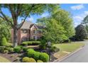 Beautiful brick home showcasing lush landscaping, a well-maintained lawn, and a corner lot location at 5620 Preserve Cir, Johns Creek, GA 30005