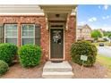 Charming brick townhome entrance with a welcoming wreath and manicured landscaping at 661 Village Field Nw Ct, Suwanee, GA 30024