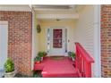 Close-up of a charming front porch with red steps and potted plants at 3095 Willow Park Dr, Dacula, GA 30019