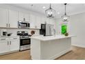 This is a kitchen with a large island, stainless steel appliances, white cabinets, and modern pendant lighting at 4240 Spring Ridge Dr, Cumming, GA 30028