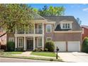 Charming brick home featuring a columned front porch and balcony with manicured landscaping at 1555 Heritage Trl, Roswell, GA 30075