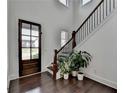 Bright foyer with a dark wood front door, hardwood floors, staircase, and neutral paint at 3180 Andover St, Cumming, GA 30028