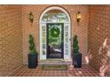 Elegant front door with sidelights, decorative wreath, and stylish potted plants at 225 Wexford Overlook Dr, Roswell, GA 30075