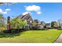 Brick home featuring a well-manicured lawn, mature trees, and a professionally landscaped yard at 3855 Greenside Ct, Dacula, GA 30019