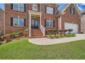 Beautiful brick home with a front porch and meticulously maintained landscaping around the entrance and garage at 9843 Talisman Dr, Alpharetta, GA 30022