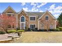 Charming two-story home featuring a stone facade, manicured lawn, and mature landscaping at 300 Morganshire Pl, Atlanta, GA 30350