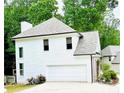 Exterior view of the home with a large garage, white siding, and a well-maintained lawn and garden at 2870 Willow Wisp Way, Cumming, GA 30040