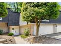 Charming townhome featuring a white door, brick accents, and mature trees, creating a welcoming curb appeal at 5250 Chemin De Vie, Atlanta, GA 30342
